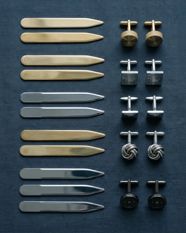 Collar stays and cufflinks arranged on slate-blue cloth