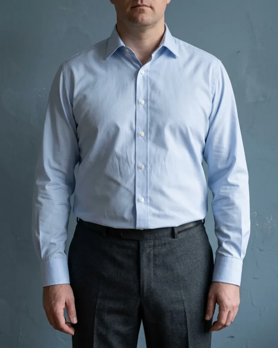 A man wearing a roomier pale blue dress shirt